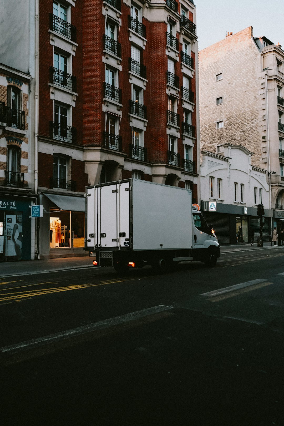 a-delivery-truck-driving-down-a-street-next-to-tall-buildings-vrdjntve-1c